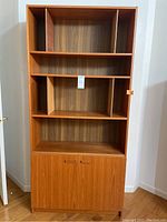 Front view of full bookcase showing upper shelves with dividers and lower cabinet doors closed