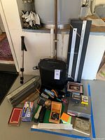 Photo showing general lot contents including shredder, mat cutter, comb binding machine, various tools, staplers, small stationery, adjustable monopod, and boxes.
