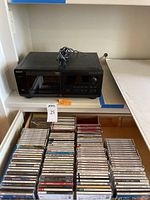 Overview of black Sony CD player on shelf with box of CDs below