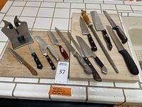 Full view of all 16 items including knives, sharpeners, and cutting boards arranged on two wooden boards.