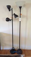 Full view of both floor lamps side by side showing the black three-bulb stick lamp and the torchiere lamp with frosted glass bowl shade