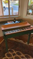 Green painted harpsichord with open lid showing keyboard and speaker