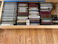 Wide view of wooden drawer containing DVD cases and guidebooks arranged in rows