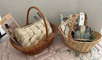 Two wicker baskets filled with yarn skeins, knitting needles, and pattern booklets