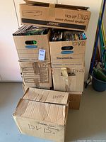 Stack of eight cardboard boxes labeled DVDs and documents, one Bose speaker box on top