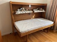 Murphy bed folded down with mattress in place, shelf above visible