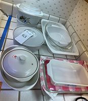 Overview of multiple CorningWare and Pyrex baking dishes and casseroles arranged on a tiled counter.