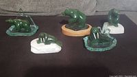 Five carved jade animal figures displayed on a flat surface including bears and walruses, each on various bases.