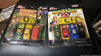 Photo showing both Donkey Kong 64 and Mario Kart 64 Racing Champions diecast sets in original packaging with signs of age and wear on packaging.