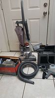 Full view of Kirby G10D vacuum upright with multiple accessories on floor including hoses, nozzles, and cleaning attachments