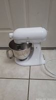 Side view of white KitchenAid stand mixer model K3M90WW showing mixing bowl attached, power cord, and minor marks on body.