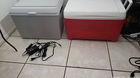 Both coolers placed on tiled floor, with Koolatron cooler grey and Igloo cooler red and white visible along with power cords for Koolatron.