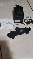 Suunto Ambit2 watch box, chest strap HR monitor, instruction manuals, and charger cable laid out on a floor.