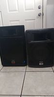 Two speakers side by side; left is a Wharfedale EVP-15P, right is a Peavey PR12. Both have visible wear; Wharfedale shows a blue LED light on.