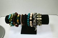 View of all 10 elastic bracelets on a black display stand showing various colors and bead styles, including turquoise, pearl, metallic, and red beads.
