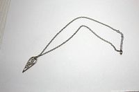 Full view of sterling silver necklace with teardrop pendant laid flat on white background.