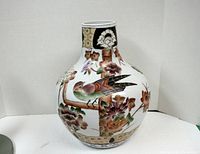 Full frontal view of the large white ceramic vase with bird and floral motifs on bulbous body and narrow neck.