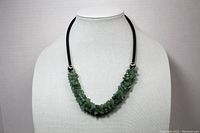 Full view of necklace on display stand showing aventurine chip stones on black leather-style rope with silver-colored beads at ends.