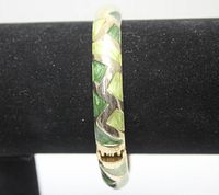 Front view of bracelet showing green and gold geometric enamel design, spring-loaded clasp visible