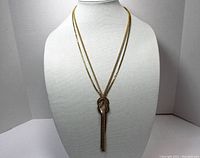 Front view of the two-strand gold tone necklace displayed on a white mannequin bust, showing the overall length and design.