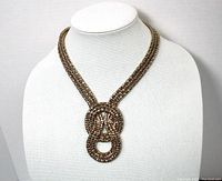 Full view of gold tone necklace displayed on a bust, showing the length and the love knot pendant detail.