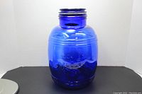 Front view of the large royal blue glass cookie jar showing overall shape and blue lid missing metal seal component.