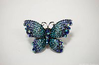 Top view of butterfly-shaped ring with blue and teal rhinestones, showing overall shape and detailing.