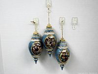 All three porcelain Christmas tree ornaments shown hanging with clear hooks. Each ornament is 4.5 inches long with blue and gold trim and framed images of sisters.
