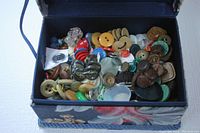 Top view of a fabric covered box filled with assorted vintage buttons in different sizes, colors and materials.