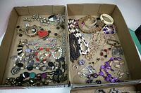 Two cardboard boxes filled with assorted costume jewelry including necklaces, bracelets, rings and earrings in mostly good condition