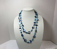 Full view of long blue mother of pearl necklace on display bust, showing overall length and arrangement of beads.