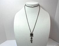 Full length view of silver tone necklace with chain and pendant on white bust