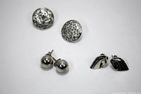 Photo showing all three pairs of sterling silver stud earrings together including cut round lacey design, polished round balls, and horse head designs.