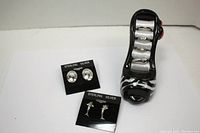Overall lot showing four rings on black shoe ring stand and two pairs of earrings on black backing cards labeled 'STERLING SILVER'
