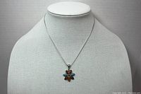 Full view of the necklace on display bust, showing chain and flower pendant.