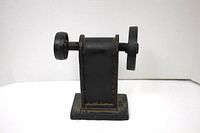 Front view of heavy iron piece showing two rotating wheels and U-shaped vertical block mounted on rectangular base