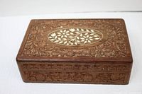 Rectangular wooden box showing detailed floral carvings on top and sides.