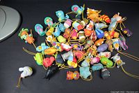 Photo showing a heap of small colorful plastic Winnie the Pooh Peek-a-Poohs characters with attached yellow strings, various animals and characters visible.
