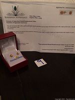 Appraisal document with details and red jewelry box containing the earrings