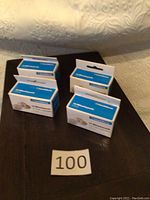 Four boxes of Leuchtturm coin capsules on a table, labeled with lot number 100.