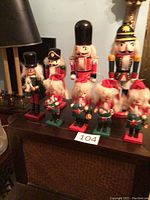 Front view showing all 8 nutcrackers on a dark surface with numbering card 104