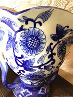 Close-up of the porcelain vase showing detailed blue floral design on white background.