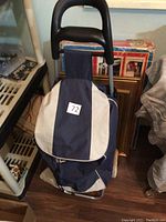 Front view of the blue and white shopping cart showing fabric bag and handle.