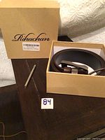 Boxed Rihachan leather belt and metal hole-creating tool placed next to box with Rihachan branding.