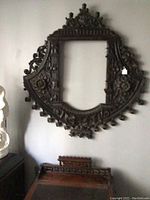 Full view of large vintage wall frame hanging on wall showcasing its elaborate decorative design and dark finish