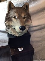 Front view showing detailed realistic wolf face sculpture mounted on black stand.