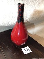 Front view of vase showing red and black Flambé glaze with fluted neck and asymmetrical opening.