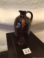 Full view of the dark brown Royal Doulton Kingsware ceramic flask with character painting and handle.