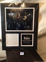 Framed photograph and display with sealed plastic showing The Beatles performing on stage as part of the lot