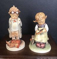 Front view of both Goebel Hummel figurines Busy Student and Doctor showing detailed hand-painting and size scale